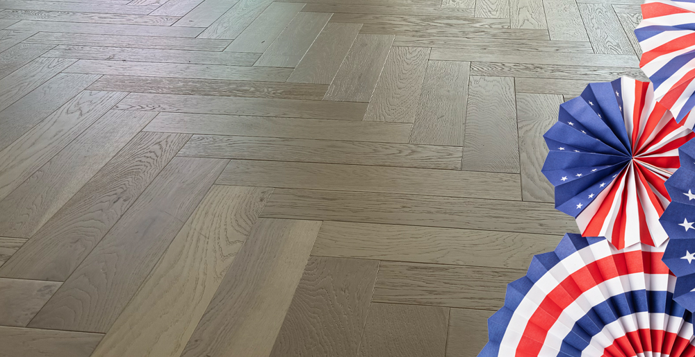 Light brown wood floor in a herringbone pattern with red, white, and blue paper fans on the right edge, decorative.
